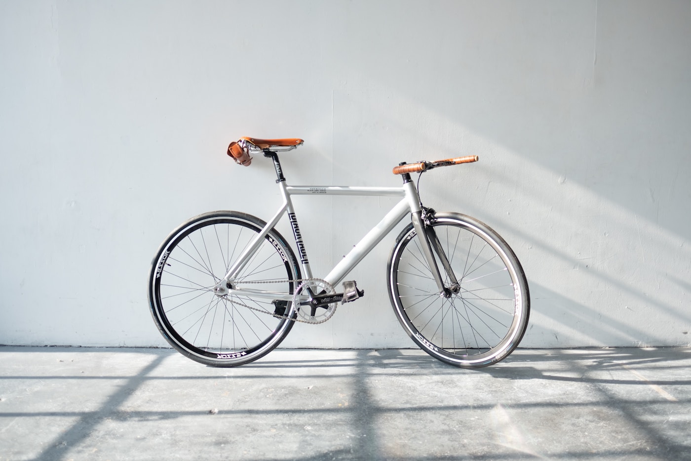 Handlebars and front wheel of a bicycle rolling along a paved path, motion blur in the background